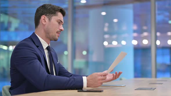 Disappointed Businessman Reading Documents in Office