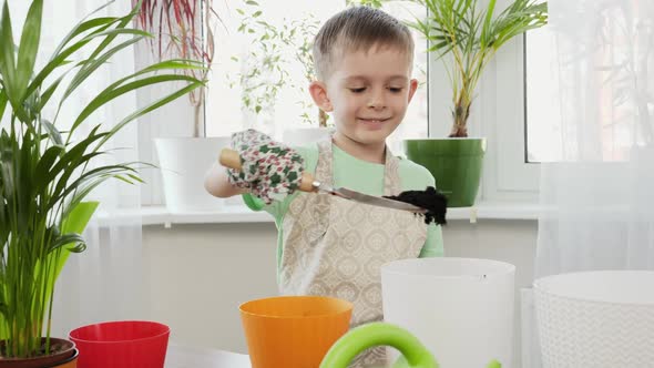 Little Smiling Boy Spreading Fertilized Soil in Flower Pots with Metal Spade