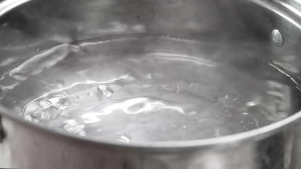 Raw spaghetti is being cooked in boiling water in a kitchen pot.