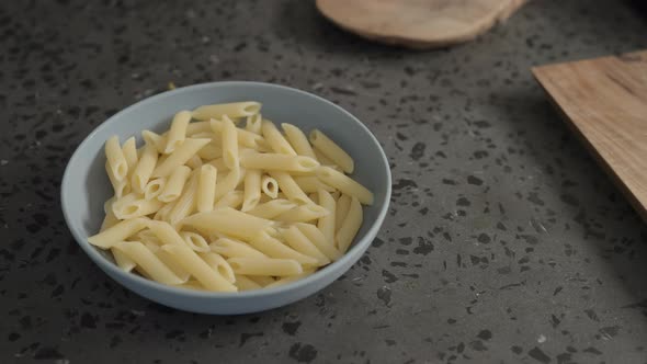 Man Add Pesto Sauce on Penne Pasta in Blue Bowl