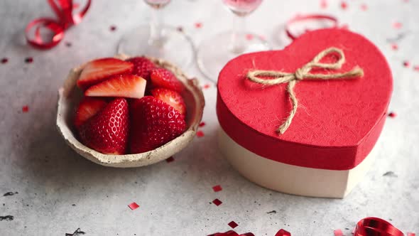 Bottle of Rose Champagne, Glasses with Fresh Strawberries and Heart Shaped Gift