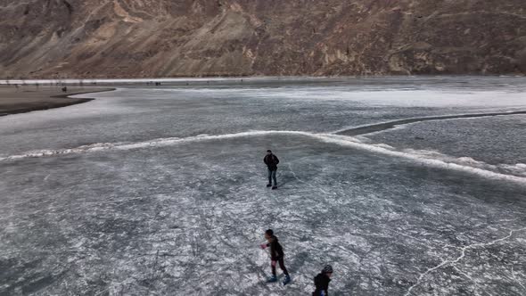 Aerial View Over Silhouette Of People Ice Skating On Frozen Khalti Lake At Ghizer Valley. Circle Dol