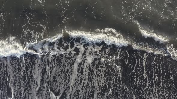 Aerial View Powerful Ocean Waves at Black Volcanic Beach Crashing and Foaming.