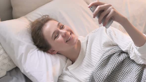 Top View of Online Video Chat by Young Woman Laying in Bed