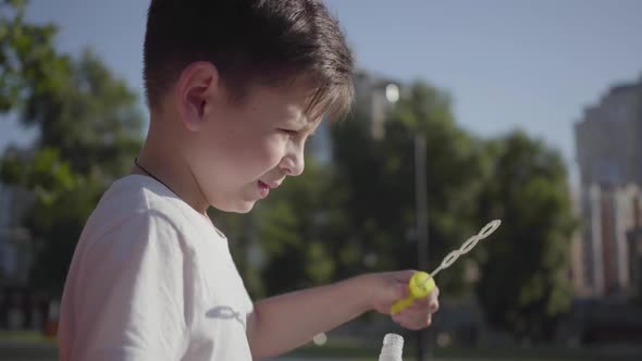 Portrait of Pretty Little Boy Blowing Soap Bubbles