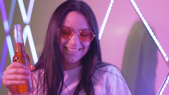 Close-up of Joyful Relaxed Woman with Colorful Beer Dancing in Night Club. Portrait of Charming