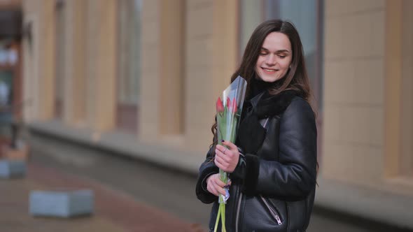 Portrait of a Happy Girl with a Tulip on the City Street