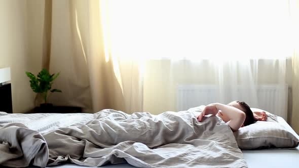 child lying on the bed in the bedroom and stretches after waking up in the morning