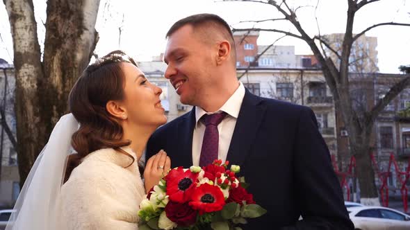 Rays of Sun Between Newlyweds Standing on Street and Look at Each Other Gently