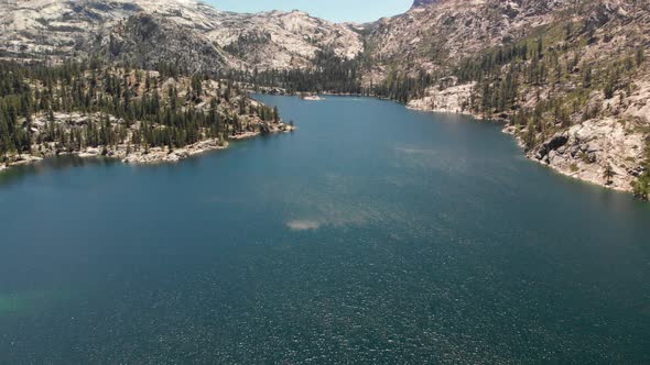 Expansive aerial view of a high Sierra lake with snowy granite peaks in the distance.