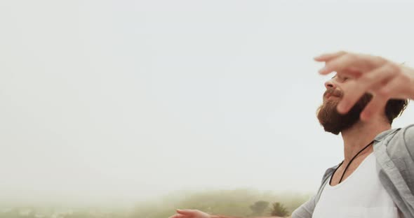 Side view of Caucasian man standing with arms outstretched on the beach 4k