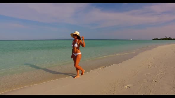 Single female sunbathes on marine island beach break by turquoise lagoon with white sandy background