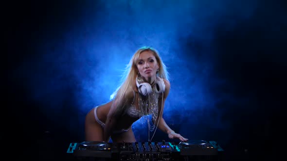 Woman DJ in White Headphones Dancing Behind the Decks