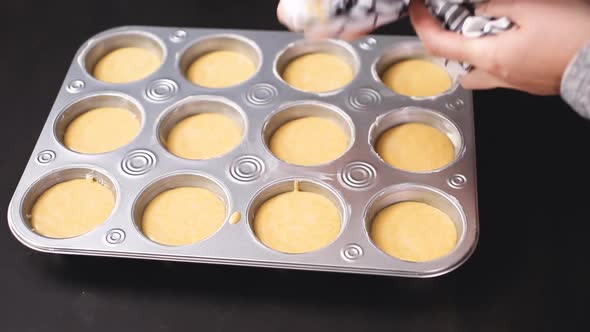 Step by step. Filling metal muffin pan with cornbread batter.