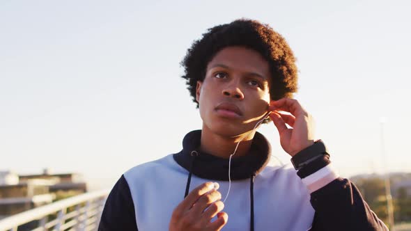 African american man putting earphones on during exercise outdoors