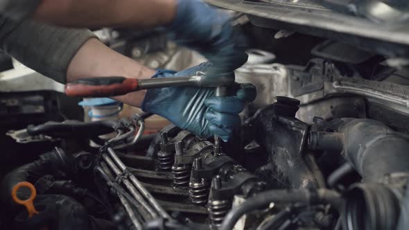 Car Mechanic Screwing Spark Plugs with Spanner