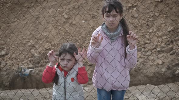 Sad children behind the iron mesh.