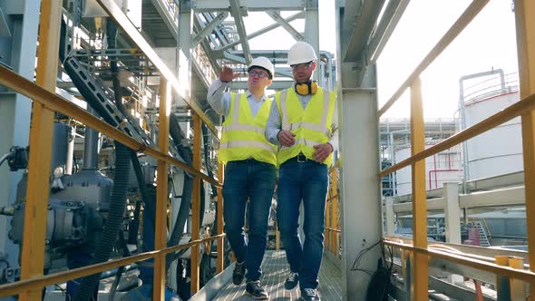 Two Engineers are Walking Along the Oil Refinery Plant