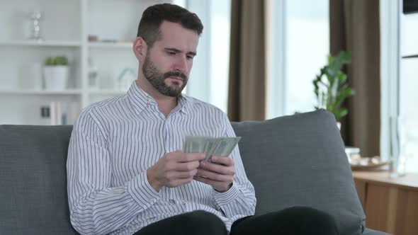 Focused Young Businessman Counting Dollars at Home 