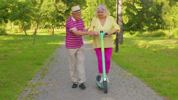 Senior Old Stylish Tourists Grandmother Grandfather Using Electric Scooter While Riding in Park