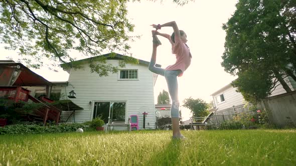 The Child Is Engaged in Acrobatics at Sunset in Back Yard. Slow Motion. Move Camera