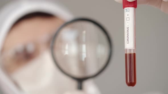 Male Scientist Is Examining a Blood Test with a Magnifying Glass