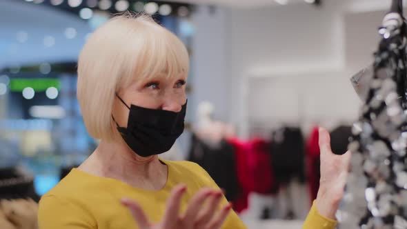 Happy Surprised Mature Woman Shopper Finds Stunning Sparkly Trendy Dress in Clothing Store Joyful