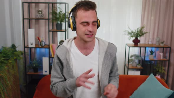 Overjoyed Young Man in Wireless Headphones Dancing Singing Listening Favorite Song in Room at Home