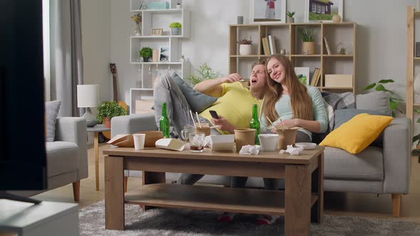 The Guy and the Girl are Lying on the Couch After Gluttony in the Living Room