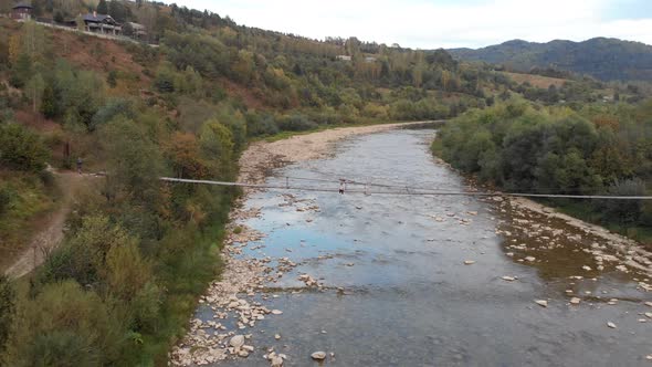 Aerial View of Tourist Woman Sit on Wooden Bridge Across Mountain River