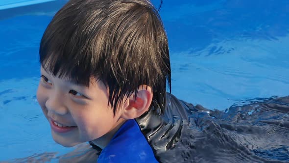 Cute Asian Boy Swimming And Playing In A Pool