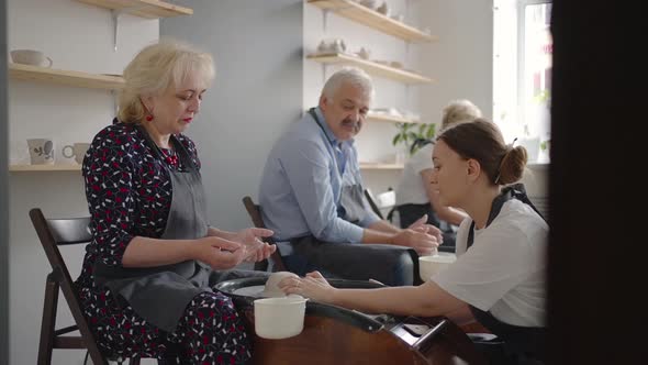 A Young Woman Teaches a Group of Senior Women and a Man of 6070 Years Old to Pottery