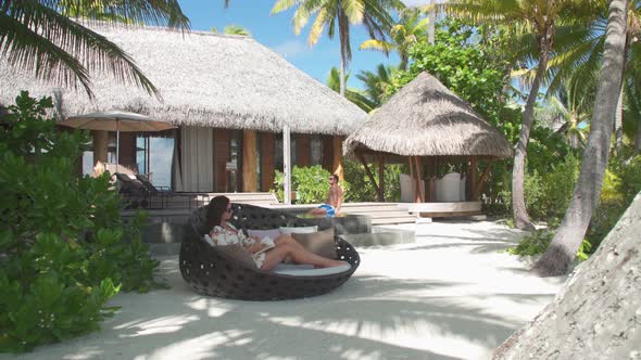 A man and woman couple relaxing and reading a book in the tropical islands in French Polynesia