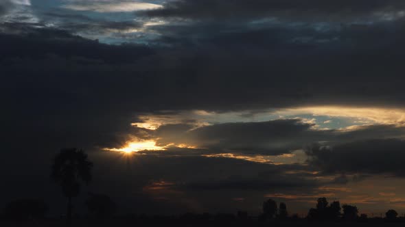 Sun Shining Through the Clouds Spreading Light Rays at Sunset