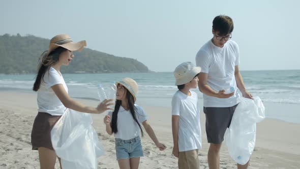 Asian family picking up plastic bottle to trash bag on the outdoor beach.