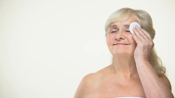 Joyful Elderly Woman Cleaning Skin With Pad, Beauty Care Procedures, Cosmetics