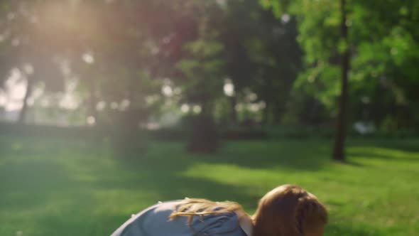 Cute Girl Picking Hit Shuttlecock with Racket in Golden Sunlight