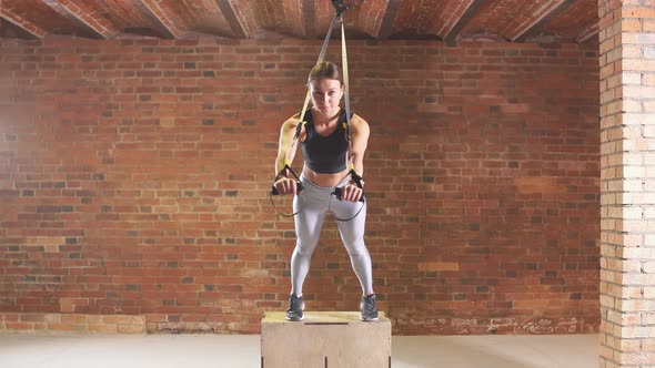 Athletic Girl Is Engaged in Crossfire. A Young Athlete Is Engaged with a Trx in the Gym