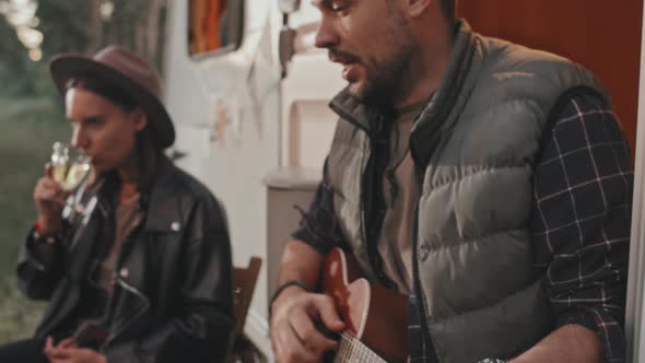 Man Playing Song for Friends at Campground