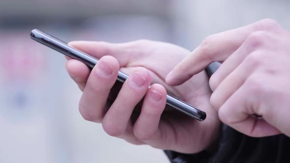 A Man Works on a Smartphone - Side Closeup on the Hands