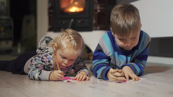 Two Happy Little Children Brother and Sister Lying on the Floor in the Room Writing and Drawing. Coz