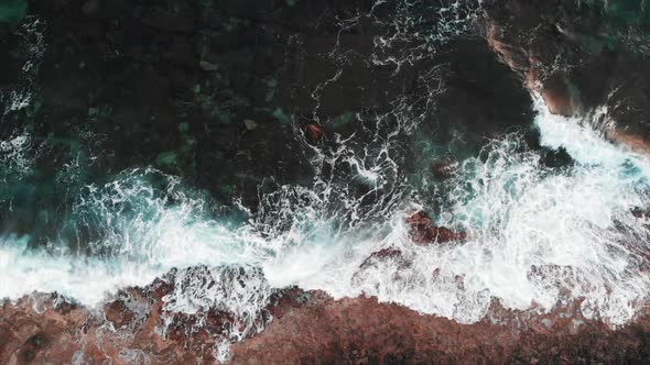 Close up Top View of Huge Stormy White Waves Bump Into Cliffs, Creating White Foam and Splashing 