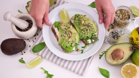 Woman Puts Homemade Soft Cheese and Avocado Sandwiches on a Table