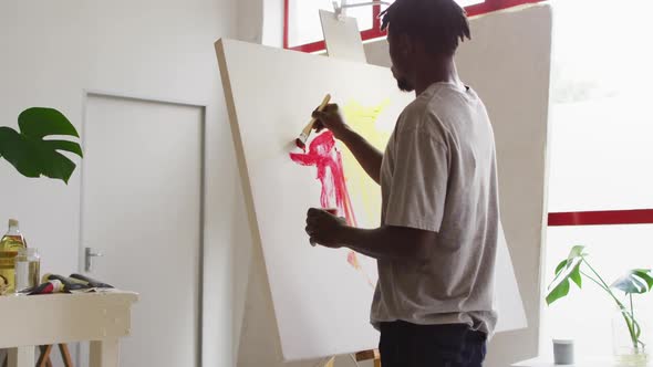 African american male artist painting on canvas at art studio