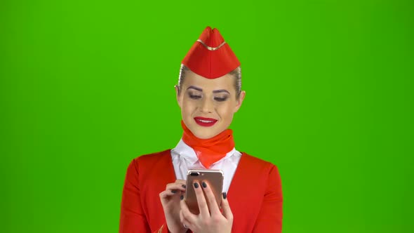 Girl in Red Attire Looking at the Phone Is Flipping Through the Pictures. Green Screen