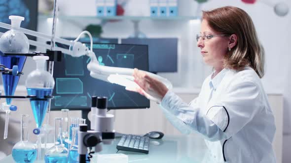 Chemist Woman Analysis a Sample Using a Big Magnifying Glass alt