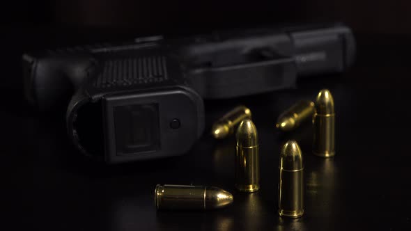 Closeup on Bullets and a Gun on a Black Table