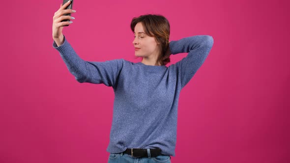 Pretty Young Black Haired Woman Taking Selfie on Pink Background