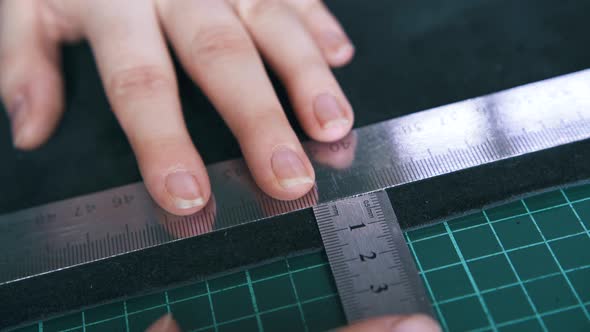Professional Tailor Measures Leather with Rulers Closeup