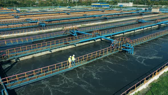 Two Male Specialists Inspecting a Modern Wastewater Treatment Plant